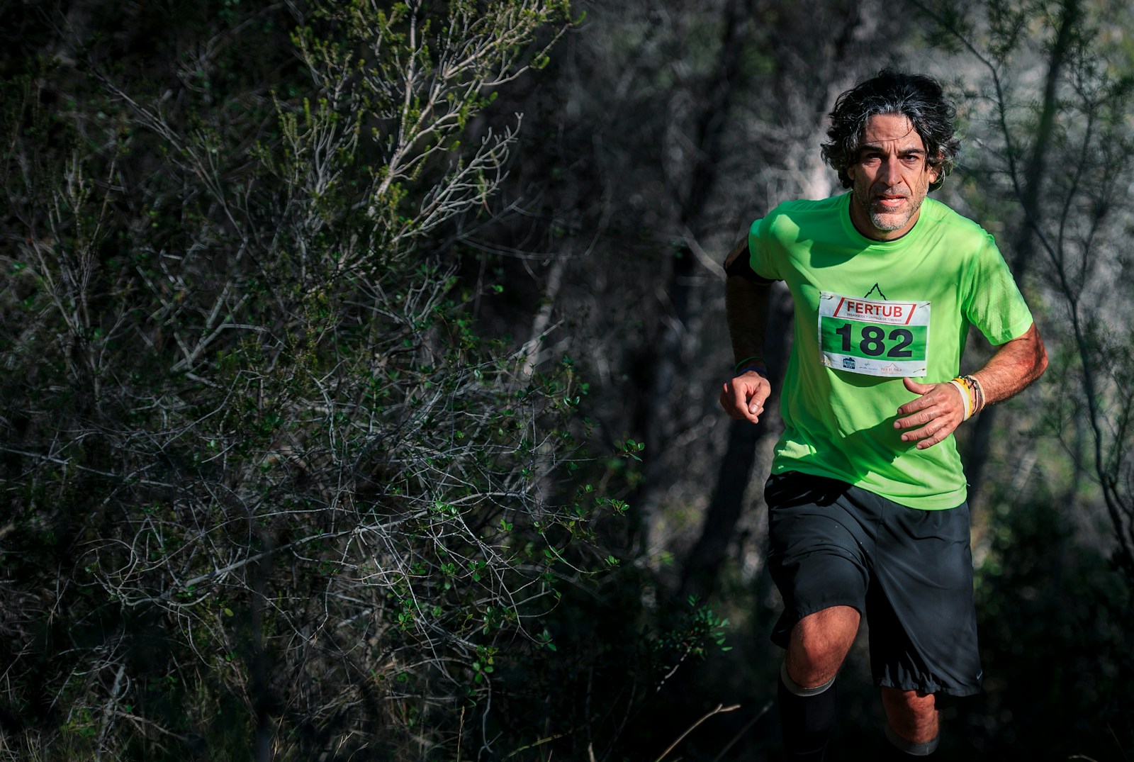 ¡Supera tus límites en las montañas con el entrenamiento personal de Entrenador Virginio Llupart en Albacete! man in green t-shirt running with 182 numbered shirt